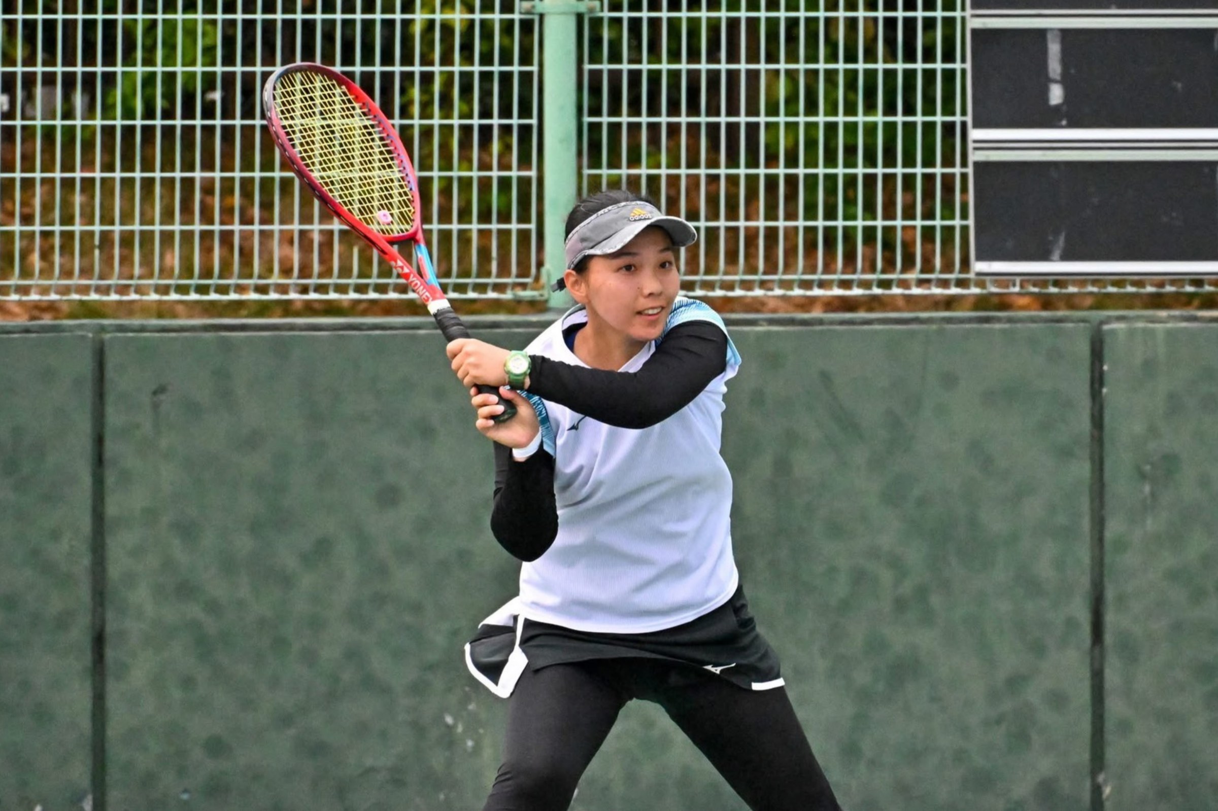 試合でプレーする中京大学硬式庭球部の女子主将